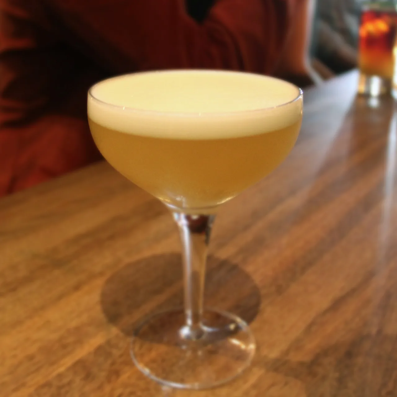 Whisky sour com espuma servido em taça coupe